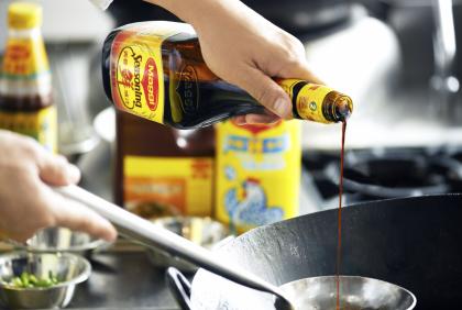 Chef adding Maggi Seasoning to his cooking.